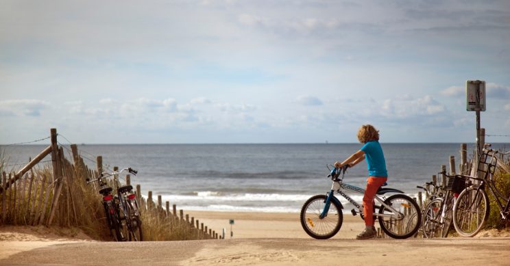 Jongen met zijn fiets bij het strand